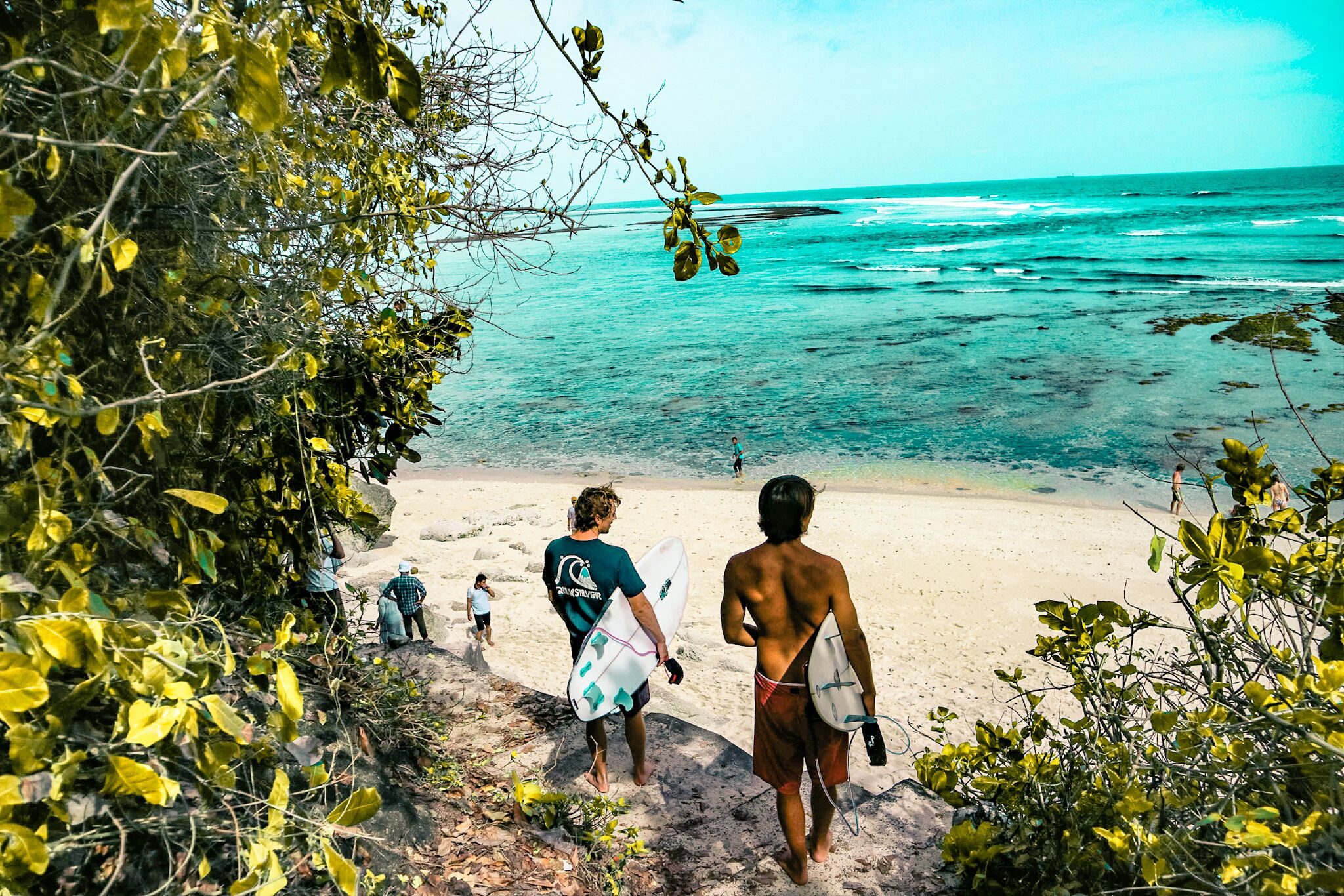 Surfers arriving at a tropical Bali beach